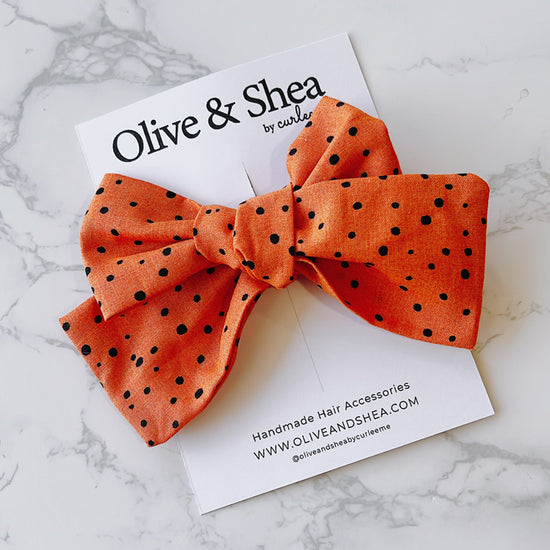 Handmade orange hair bow with black polka dots