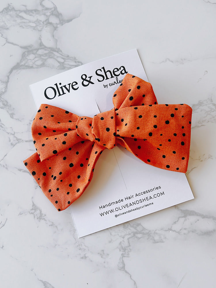 Handmade orange hair bow with black polka dots