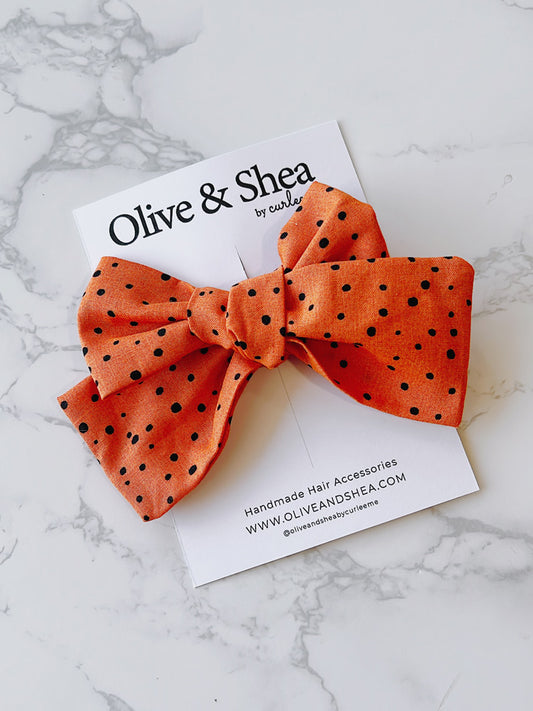 Handmade orange hair bow with black polka dots