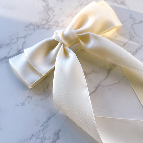 An ivory satin ribbon bow with long tails