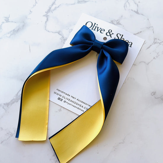 A satin hair bow ribbon in navy blue and yellow.