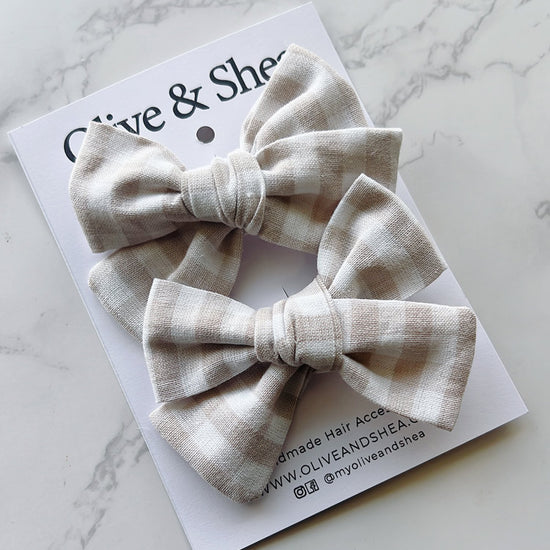 Two beige bow hair accessories on a white card with 'Olive & Sheen' branding.